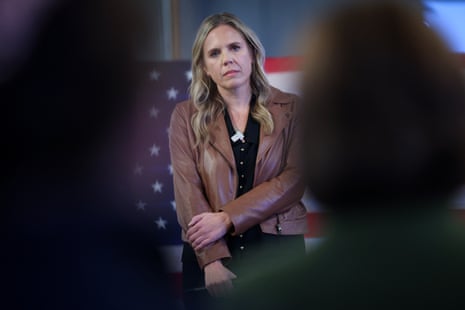 woman stands with arms crossed, listening during a town hall campaign event