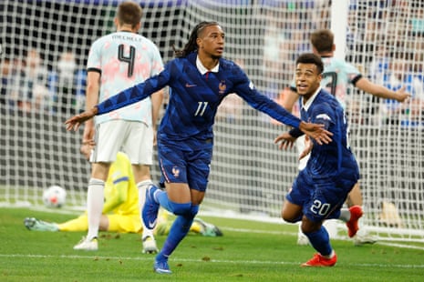 Michael Olise celebrates his goal with arms outstretched, running towards a teammate