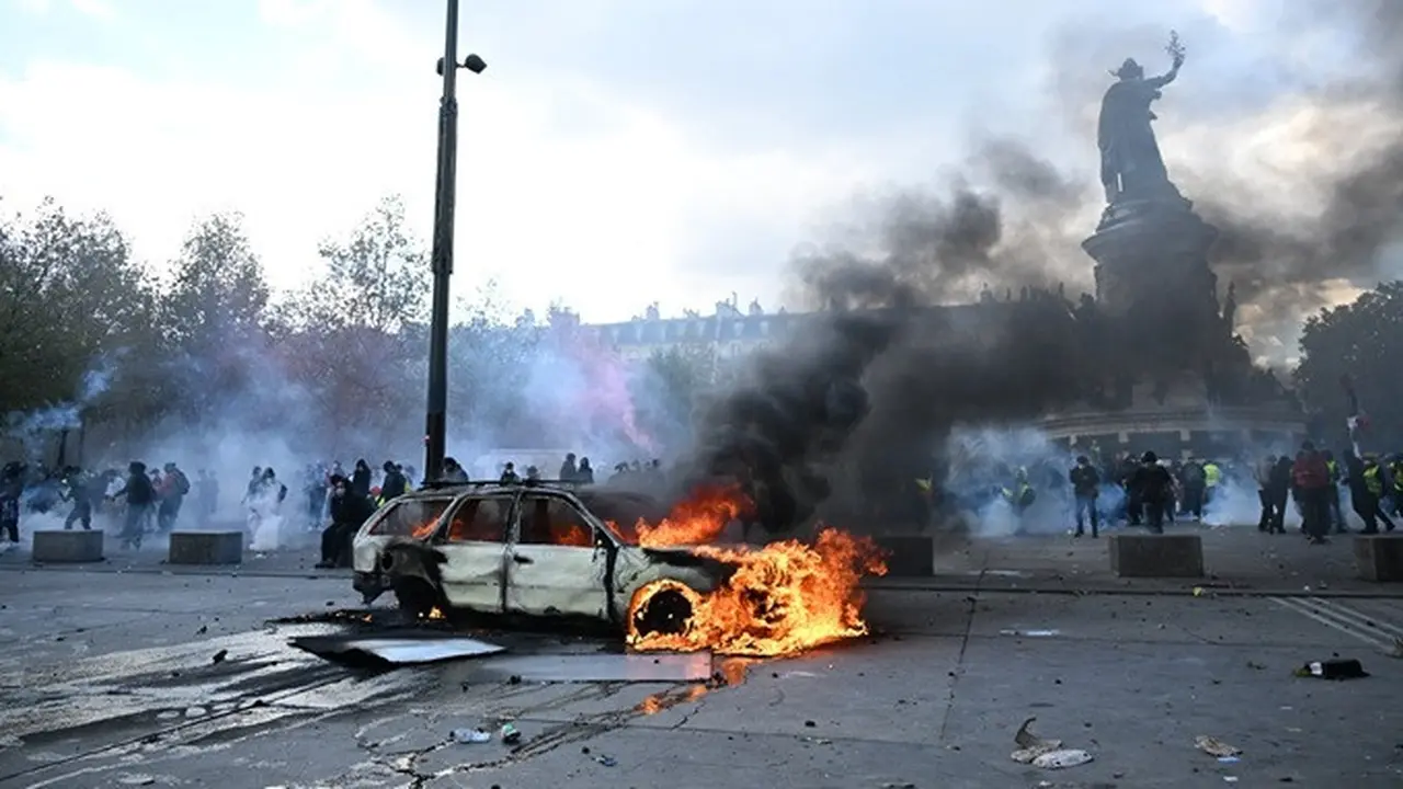 Sebuah mobil terbakar di Place de la Republique, Paris, Prancis, saat berlangsungnya demonstrasi memprotes kenaikan biaya hidup pada Sabtu (17/10/2026).