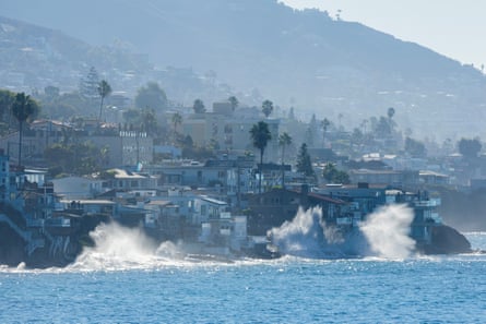 Large waves crash against Laguna Beach’s coastline, splashing near hillside homes